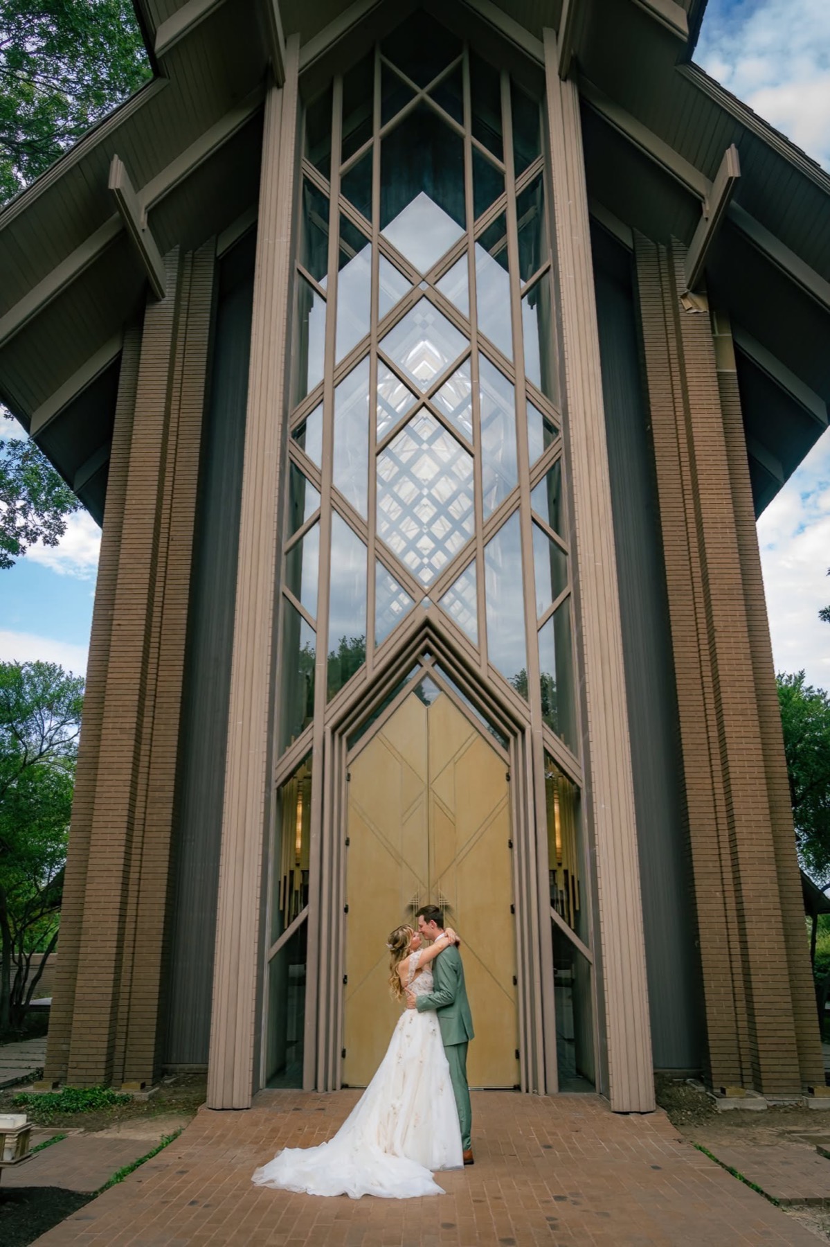 Newlyweds embrace before a geometric chapel facade