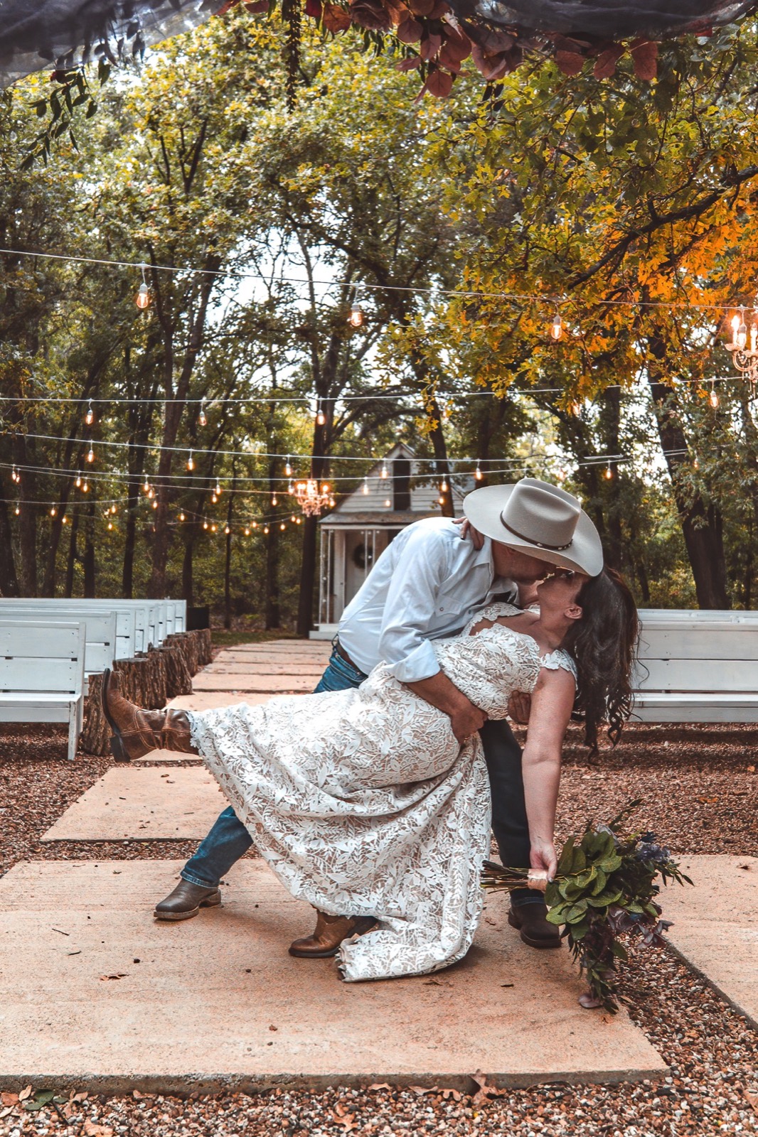 Newlyweds share a joyful dip beneath string lights