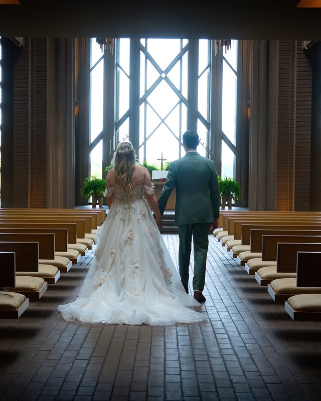 Newlyweds walk together through a sunlit chapel