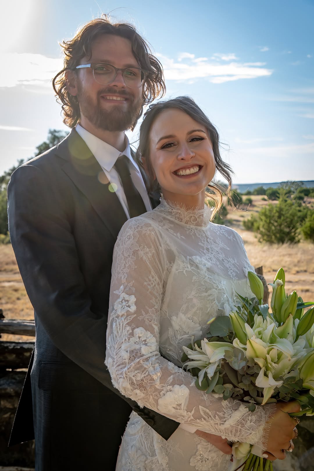 Newlyweds smile together beneath a blue sky